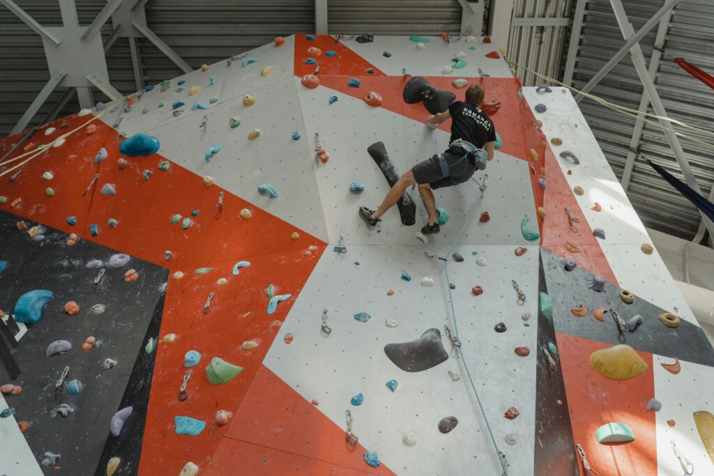 Man climbing colorful indoor wall with determination and skill in a gym setting.